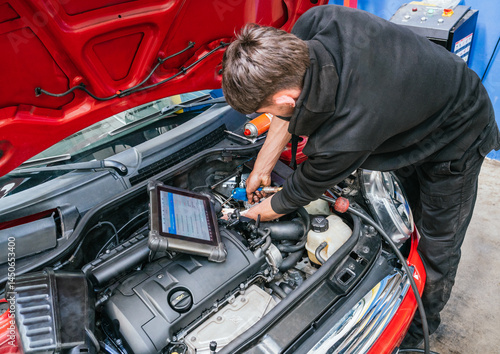 Car mechanic repairing engine using diagnostic software on tablet