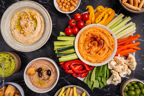Obraz na płótnie Various hummus dips. Hummus plate with vegetable snacks. Carrot, cucumber, tomato, celery sticks, dry crackers and olive, top view. Vegan and traditional hummus as healthy and vegan snack. w salonie