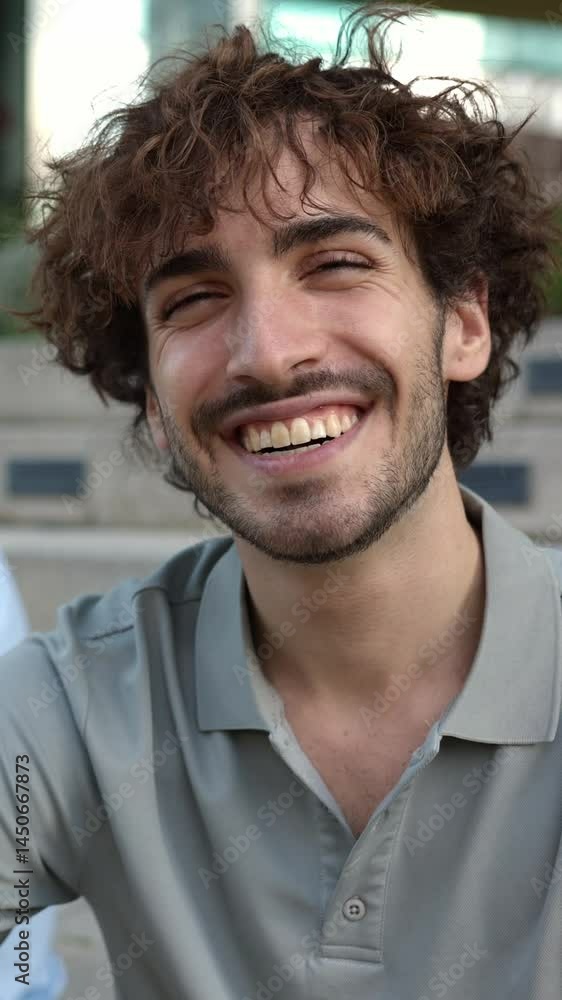 Portrait of happy young man smiling at camera with multiracial female friends talking on the background. International youth friendship concept Portrait of happy young man smiling at camera with multiracial female friends talking on the background. International youth friendship concept