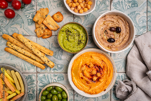 Various hummus dips in different colours. Hummus with dry crackers, top view. Vegan and traditional hummus as healthy and vegan snack.