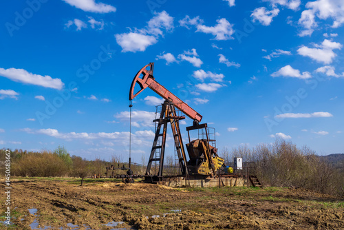 Fotografía Old Oil Pump Jack Operating in Rural Field