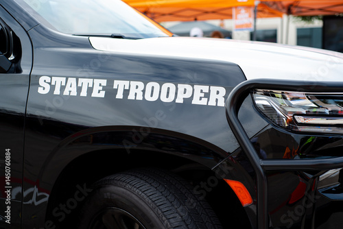 Side view black SUV State Trooper patrol vehicle with push bumper steel frames mounted used to push disabled vehicles away from danger or clear the roadway ensuring public safety, police bullbars
