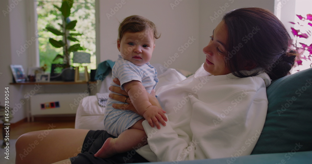 Mother smiling at her baby while holding them on her lap in a sunlit living room, creating a warm and affectionate moment of connection between mother and child-SD 480p Mother smiling at her baby while holding them on her lap in a sunlit living room, creating a warm and affectionate moment of connection between mother and child-SD 480p