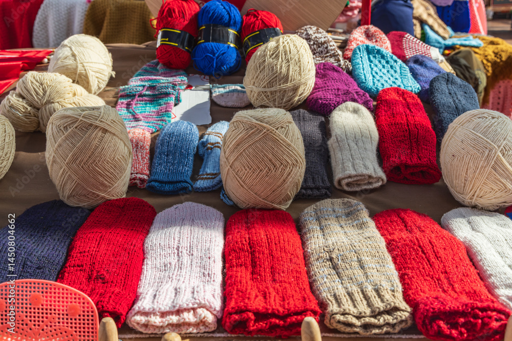 Yarn and knitted mittens for sale at an outdoor market.