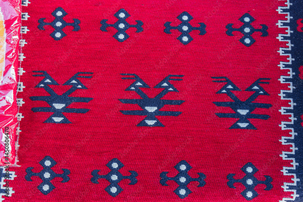 Geometric pattern in a brightly colored red woven rug.