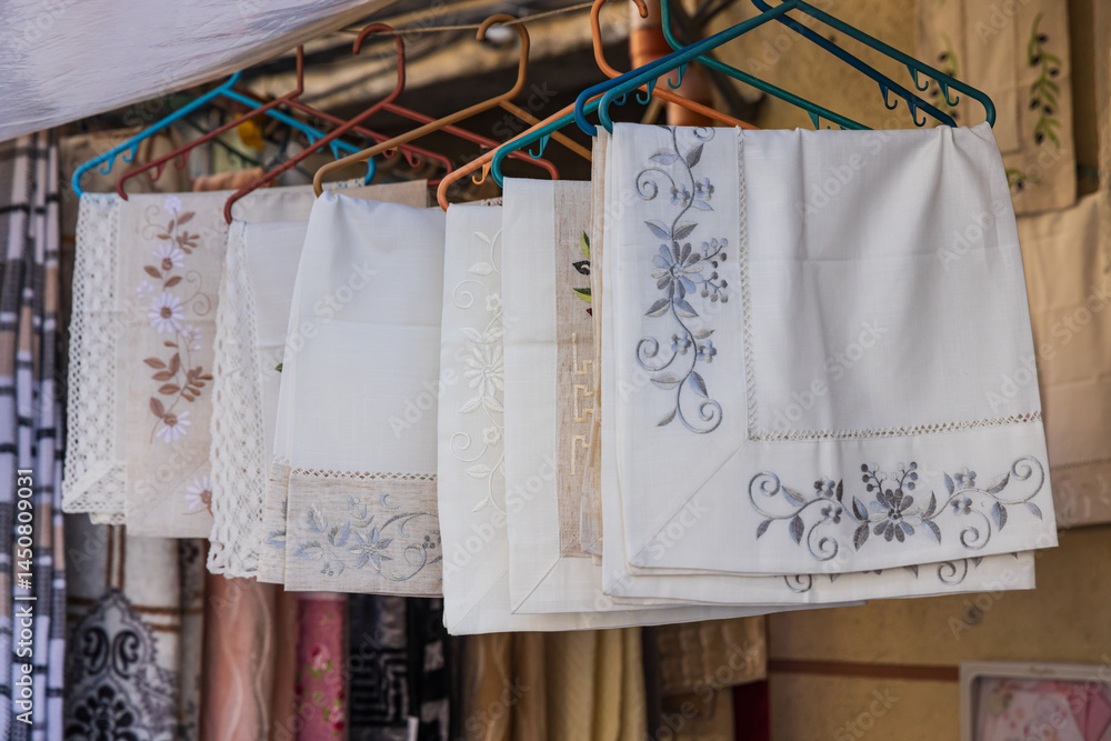 Embroidered table cloths for sale at an outdoor market.