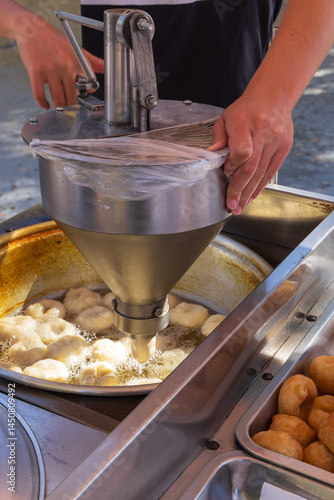 Obraz na płótnie Street vendor frying fresh donuts at outdoor market. w salonie