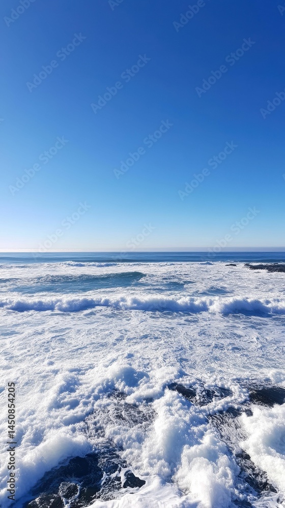 Ocean waves crash on rocks, clear blue sky. Ocean waves crash on rocks, clear blue sky.