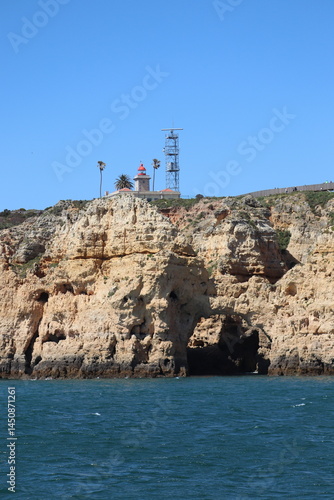 a photo of a rocky southern coast of portugal on a sunny summer day with ocean in the background