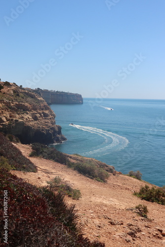 a photo of a rocky southern coast of portugal on a sunny summer day with ocean in the background