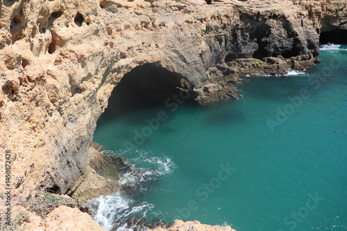 a photo of a rocky southern coast of portugal on a sunny summer day with ocean in the background
