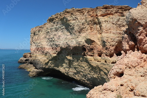 a photo of a rocky southern coast of portugal on a sunny summer day with ocean in the background
