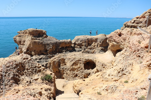 a photo of a rocky southern coast of portugal on a sunny summer day with ocean in the background