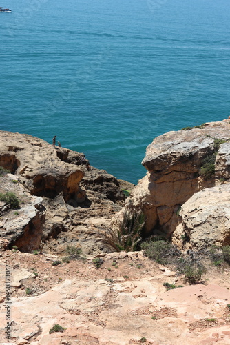 a photo of a rocky southern coast of portugal on a sunny summer day with ocean in the background