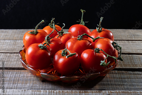 фотографія Dish with several fresh tomatoes in a rustic setting.