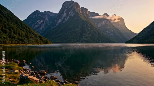 Peaceful Mountain Landscape with Calm Lake, Lush Shoreline, and Golden Sky Reflection