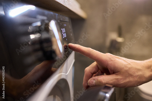 Obraz na płótnie Individual Interacting with a Modern Washing Machines Control Panel for Efficient Laundry Tasks w salonie