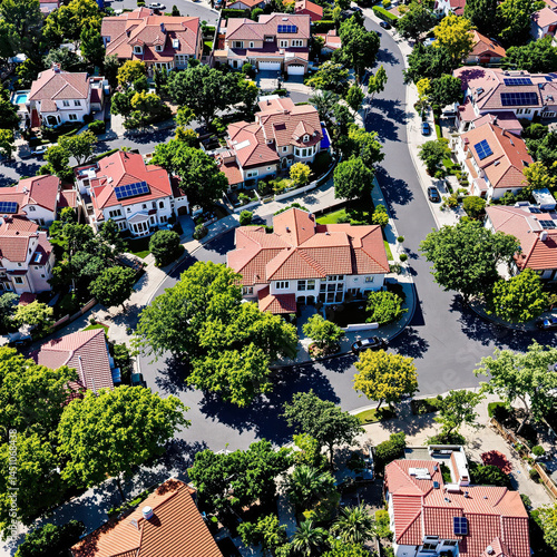 aerial view of a sun-drenched residential neighborhood with uniform houses and lush green trees