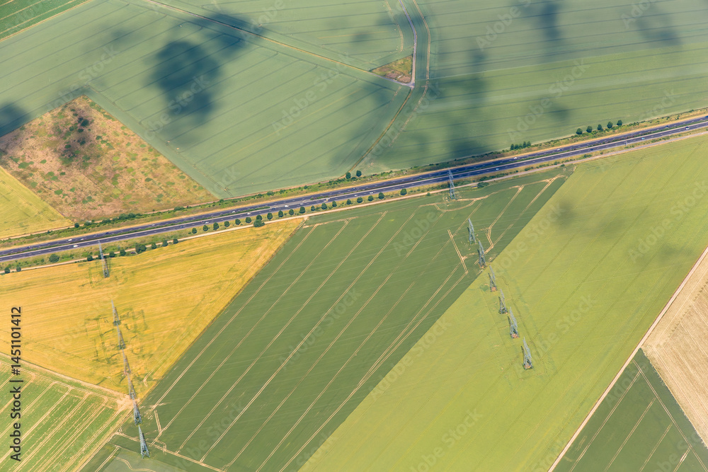 areal of beautiful landscape near Paris with green fields,street and electric pylons for renewable energy