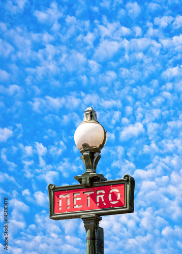 Obraz na płótnie Parisian metro sign in red with a lamppost with blue soft cloudy sky w salonie