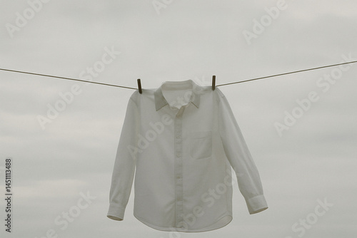 White shirt on clothesline under humid overcast sky with quiet rainy morning mood