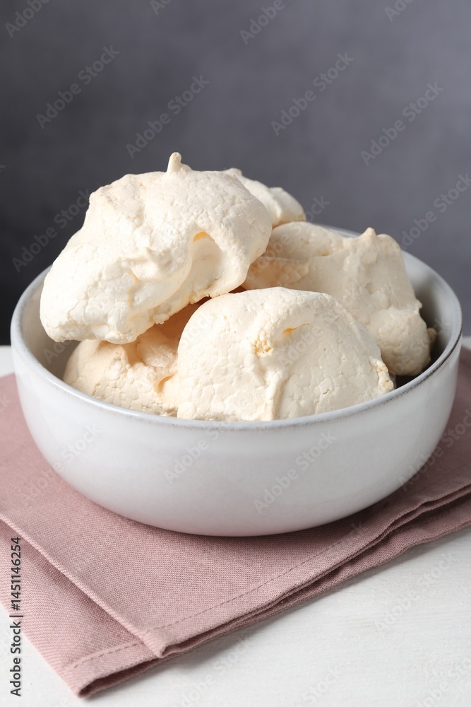 Delicious homemade meringue cookies in bowl on light table against gray background, closeup Delicious homemade meringue cookies in bowl on light table against gray background, closeup