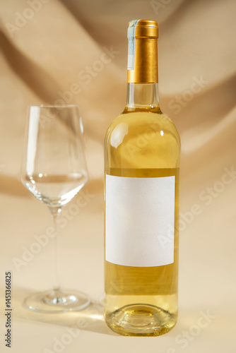 A wine glass and bottle of white wine on yellow background.