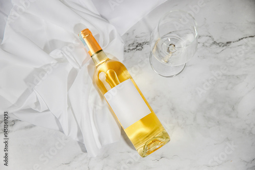 Unopened white wine bottle with blank label, empty wine glass. Wine bottle mockup. View from above

