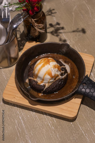 Canvas-taulu A sizzling brownie dessert is presented in a small cast-iron skillet on a light wooden board