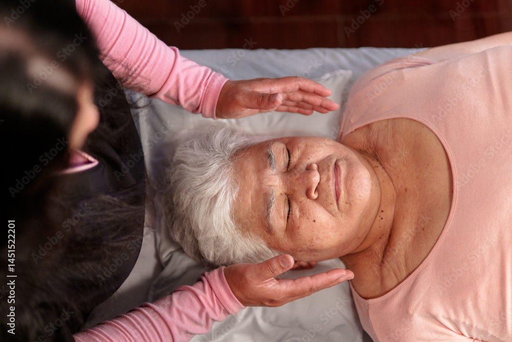 Overhead view of a Reiki practitioner channeling energy to a senior woman during a healing session Overhead view of a Reiki practitioner channeling energy to a senior woman during a healing session