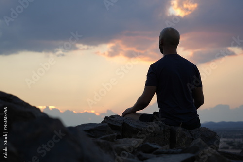 Foto Man sitting in meditation during setting sun.