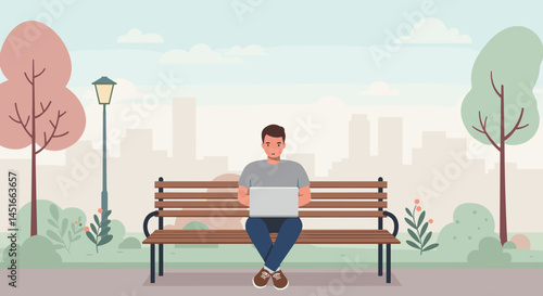 Young man working on laptop while sitting on a park bench  