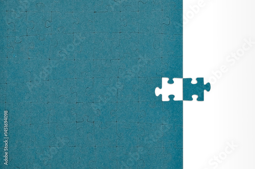 Teal jigsaw puzzle with one missing piece placed on the side over a brown background.
