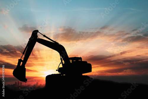Crawler excavators silhouette are digging the soil in the construction site. With blue sky and clouds of on sunset background