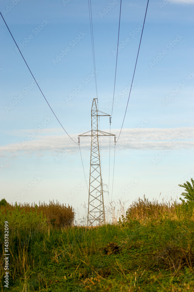 Krajobraz słup elektryczny wśród pól i łąk błękitne niebo.