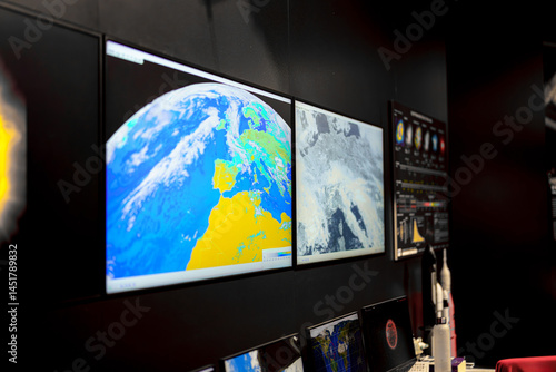 Displays show detailed satellite imagery in a monitoring room for a space exploration center