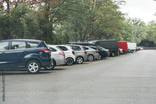 Bilde på lerret Parking lot filled with vehicles among trees on a cloudy day in a quiet urban ar