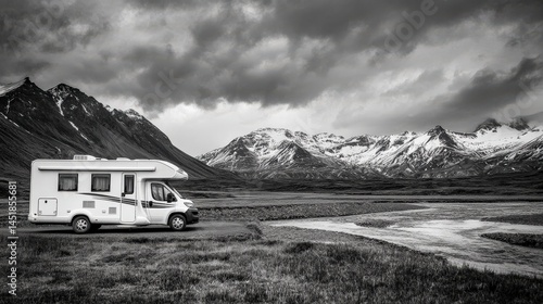 Scenic camper van parked beside stunning mountain landscape in black and white emphasizing outdoor adventure and tranquility