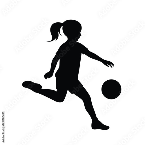 Silhouette of a young girl playing soccer, kicking the ball