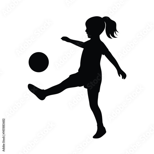 Silhouette of a young girl playing soccer, kicking the ball