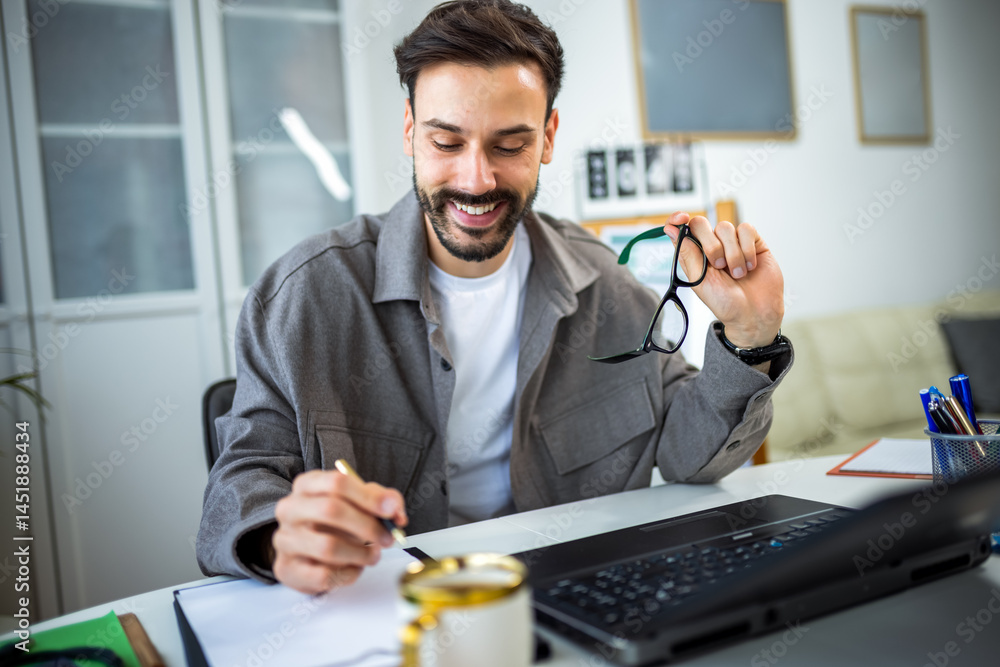 Young man working remotely from home on his laptop. Young man working remotely from home on his laptop.