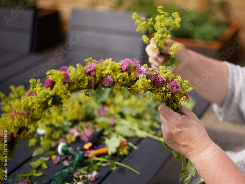 The hands of a woman building a midsummer wreath of flowers for the traditional swedish midsummer celebration