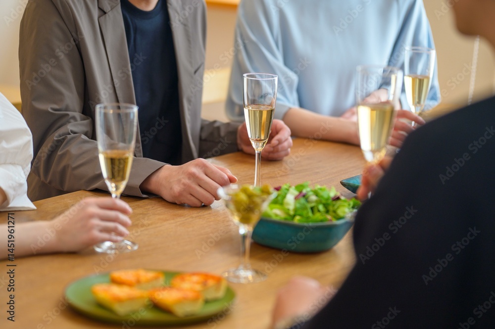 シャンパングラスを囲んで穏やかに会話を楽しむ男女グループの静かな時間 シャンパングラスを囲んで穏やかに会話を楽しむ男女グループの静かな時間