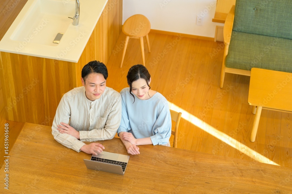 上から見た視点でノートパソコンに向かうカップルの落ち着いた室内シーン 上から見た視点でノートパソコンに向かうカップルの落ち着いた室内シーン