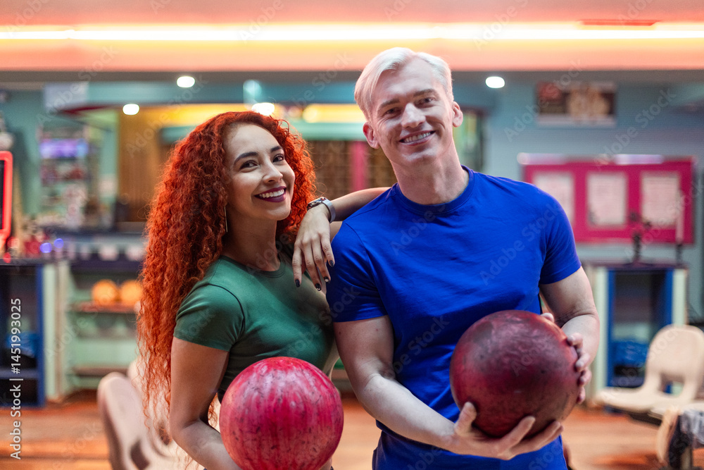 Fototapeta premium Happy couple holding bowling balls, ready for a fun night out