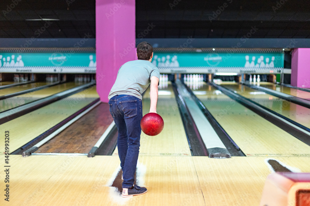Obraz premium Young man throwing bowling ball in modern bowling alley