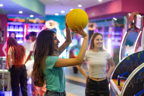 Young women playing basketball in amusement arcade