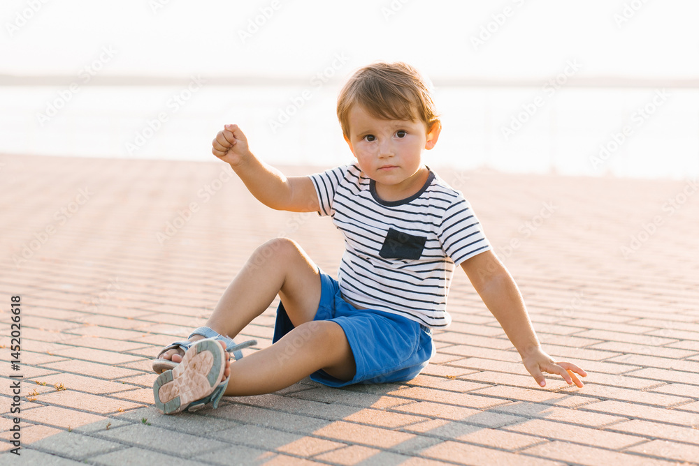 Cheerful Little Boy Sitting Outdoors on a Sunny Day