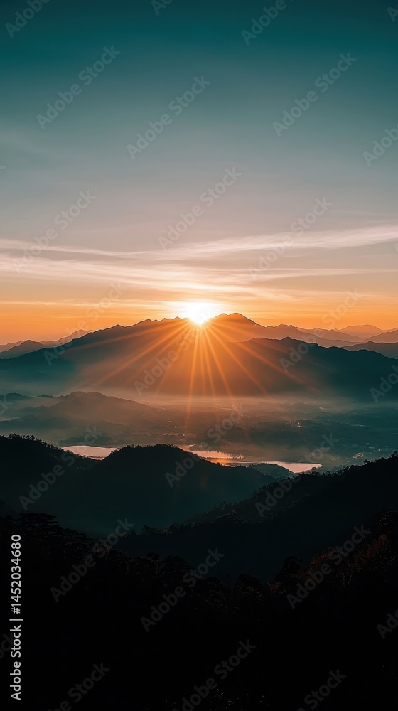 Fototapeta premium Breathtaking Sunrise Over Mountain Range with Rays of Light Illuminating the Horizon and Misty Valley Below