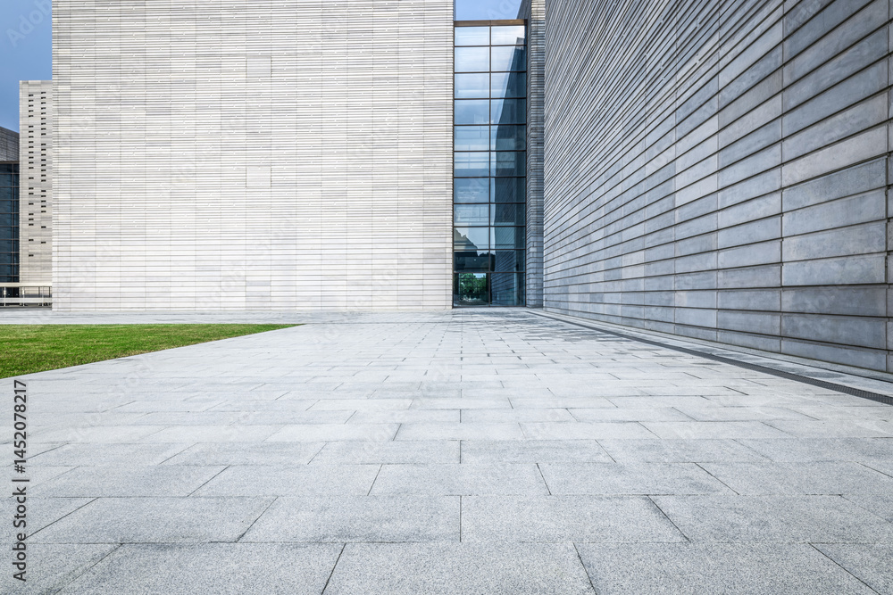 Fototapeta premium Empty square floor pavement leading to the entrance of a modern architecture office building exterior with grey walls.